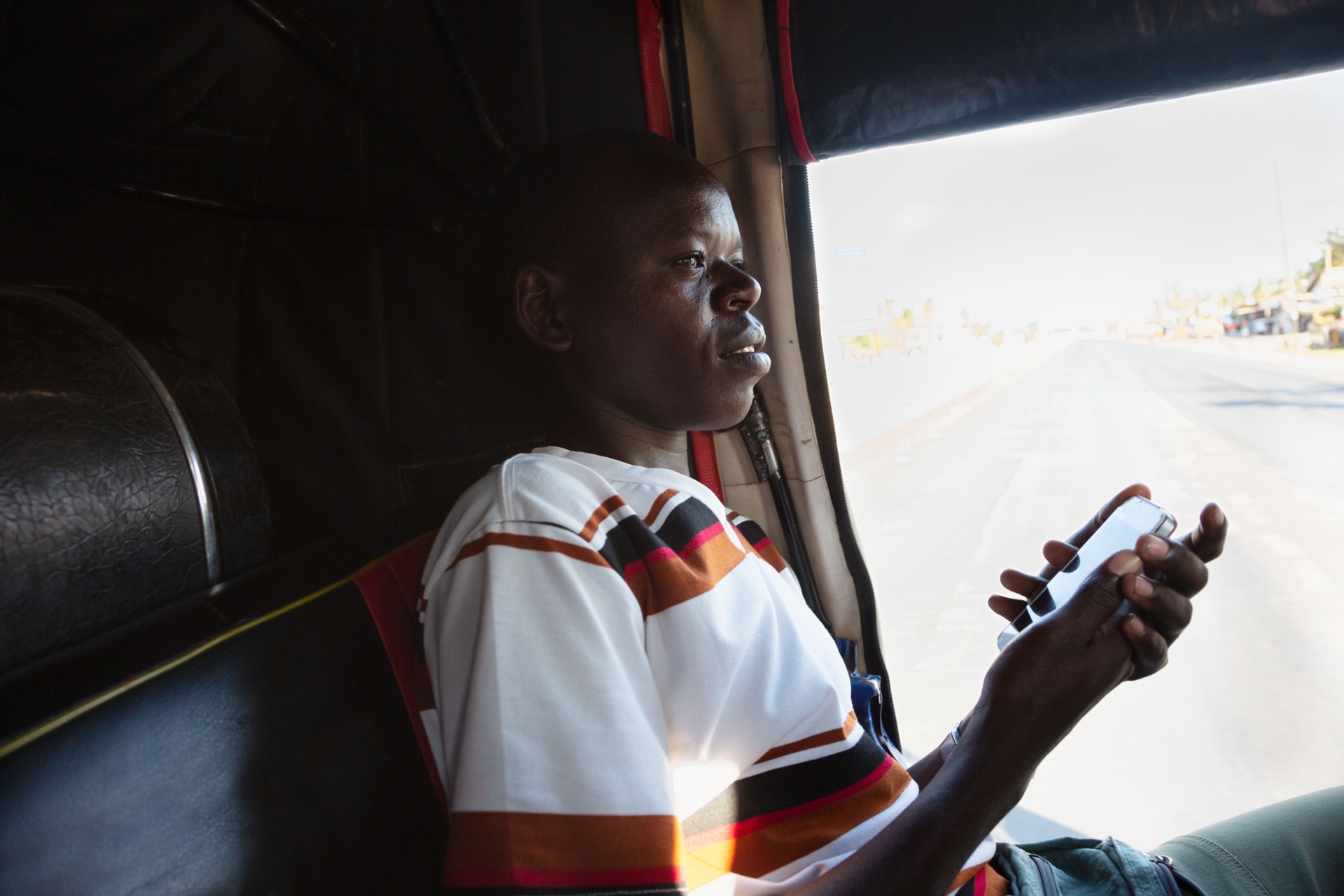 Young african man using mobile phone inside taxi